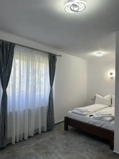 Pat dublu cu lenjerie albă într-o cameră la Casa Suciu