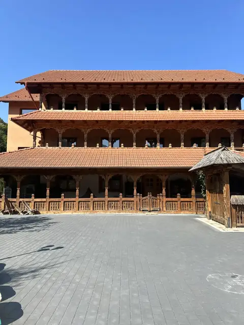Pensiunea Casa Suciu vara — fațada din lemn cu pridvoare și munți în fundal