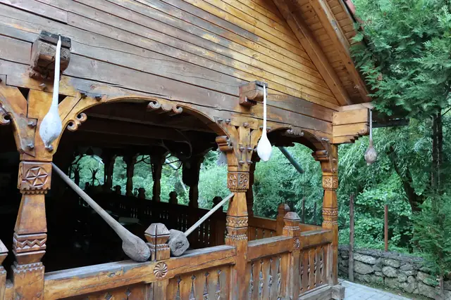 Arcade sculptate și linguri mari de lemn atârnate la foișorul pensiunii
