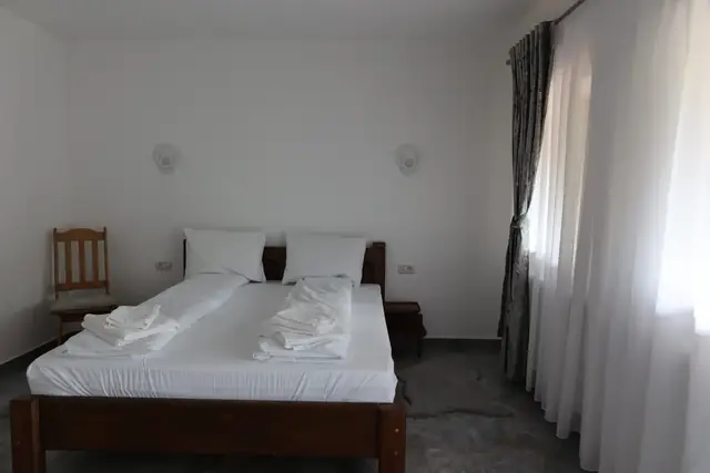 Dormitorul apartamentului family cu pat matrimonial din lemn masiv