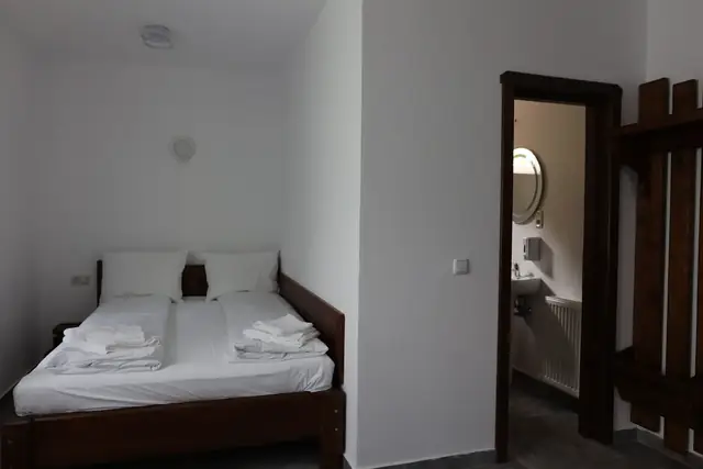 Cameră cu pat dublu și baie proprie cu lavoar și oglindă